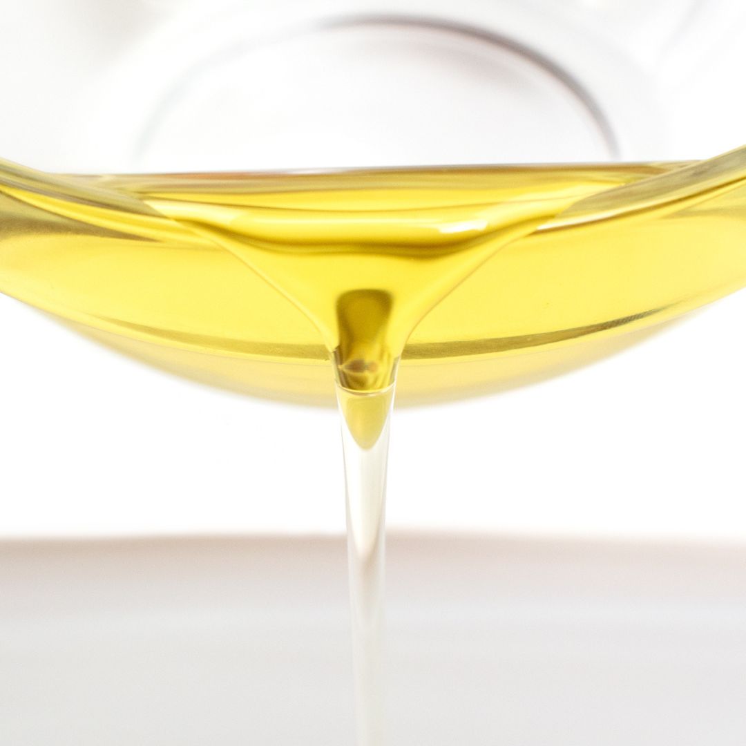 oil in a glass bottle being poured out in front of the camera