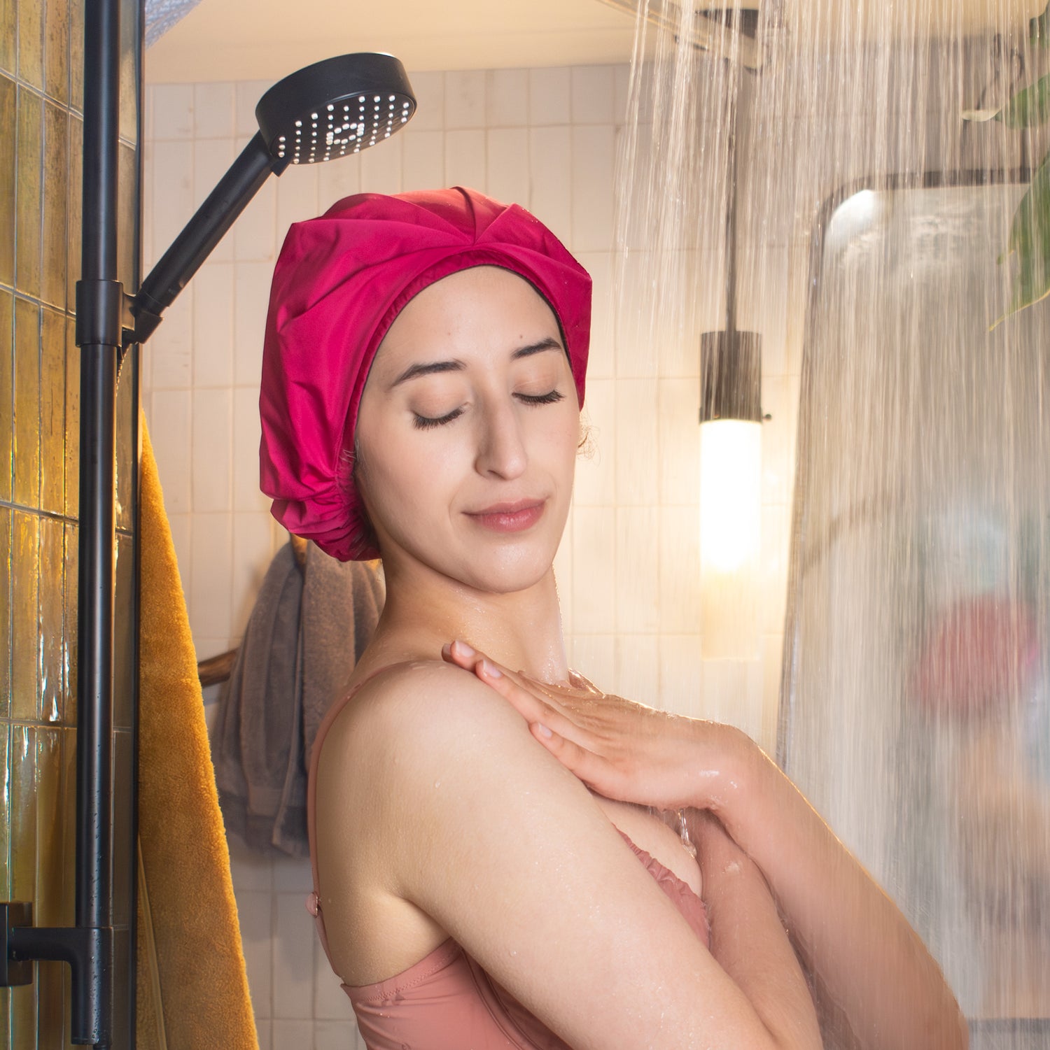 relaxed curly haired woman in the shower with her hair in a shower cap