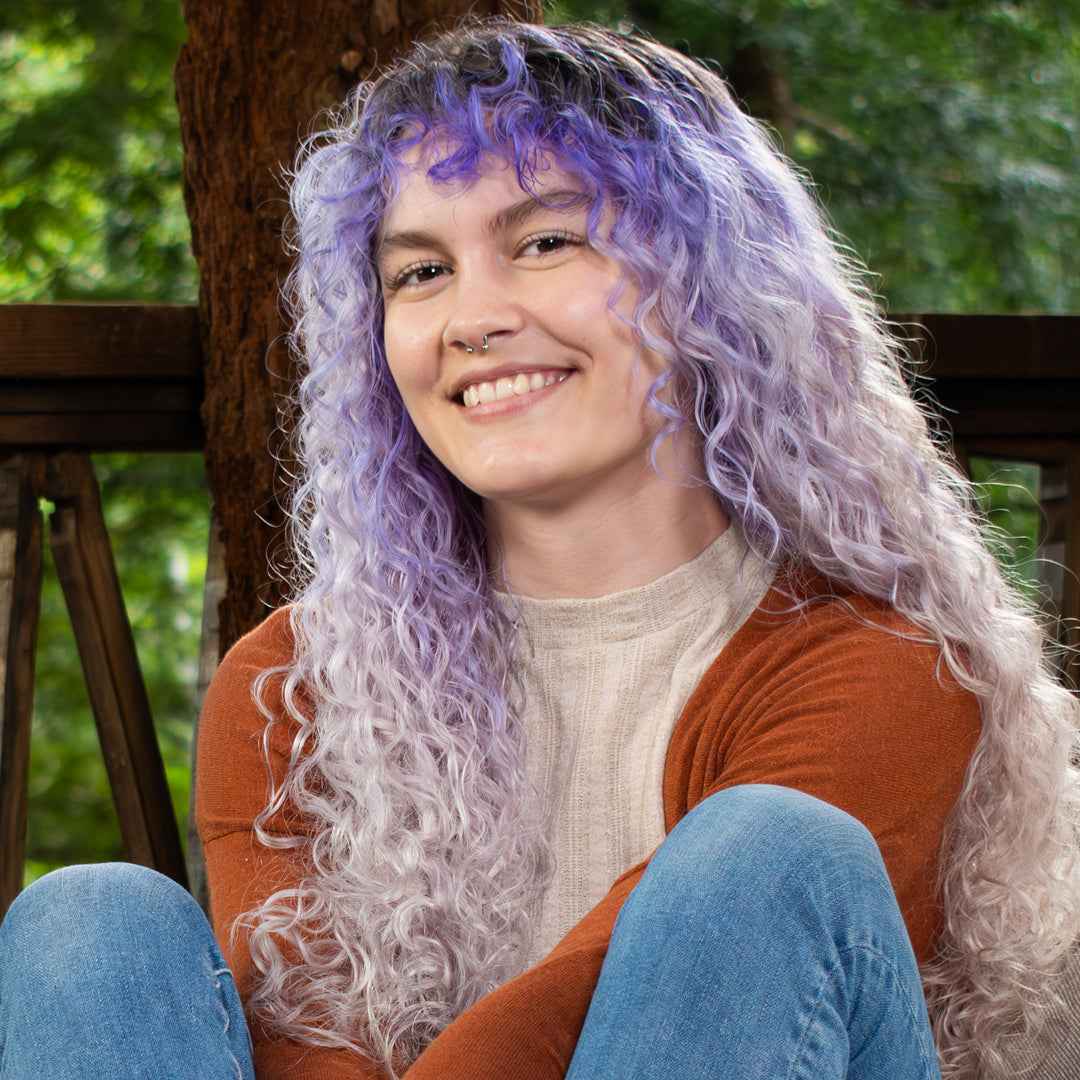 fine haired Curly woman smiling and sitting on a porch in the woods