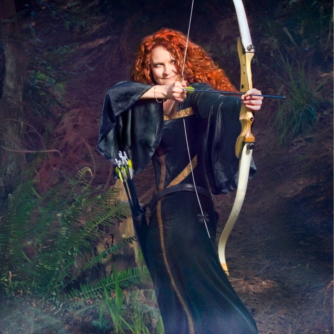 jessicurl founder, Jess McGuinty, dressed as Merida from Brave in a green dress and bow standing in a forrest