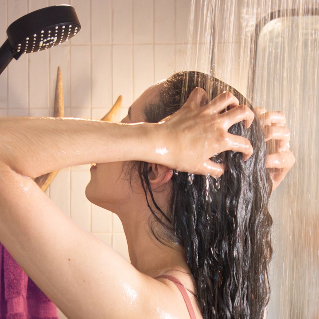 curly haired woman washing her hair in the shower