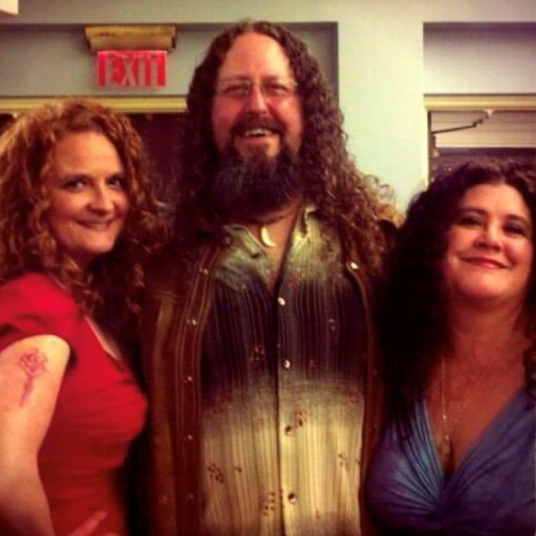 group of two women and one man smiling, all with curly hair