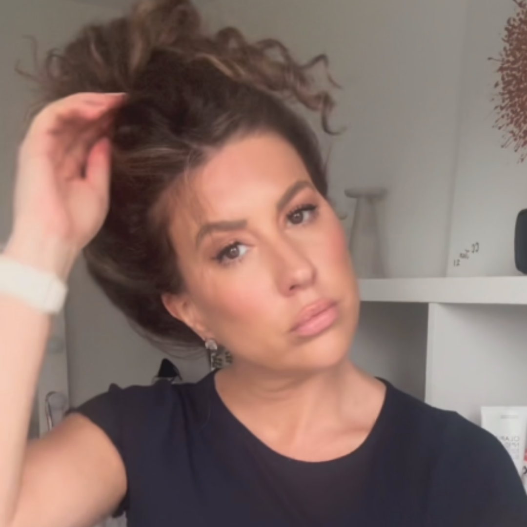 Chief Educator Claire with her hair up in a bun as she reaches to take it down