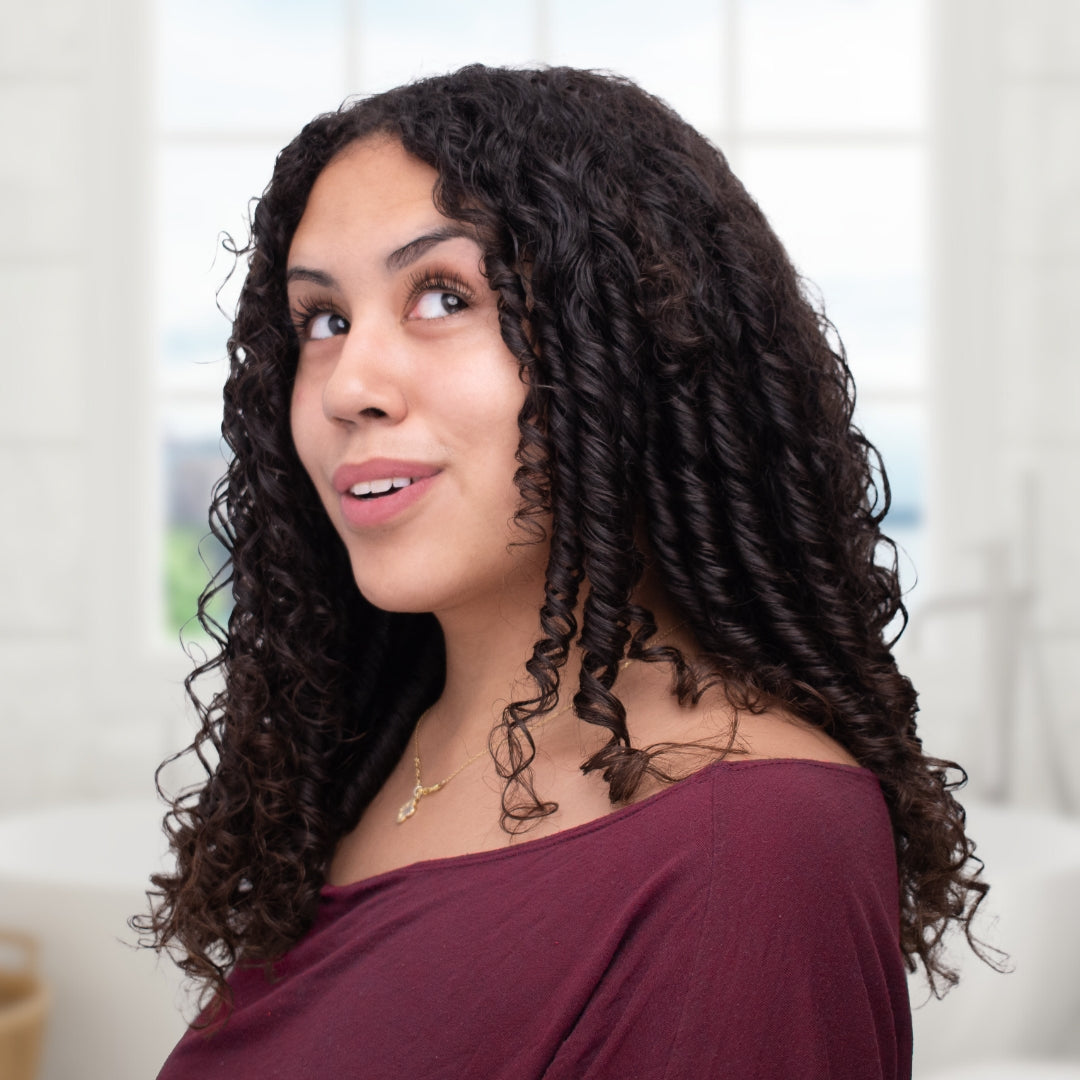 curl haired woman smiling and looking up and over her shoulder