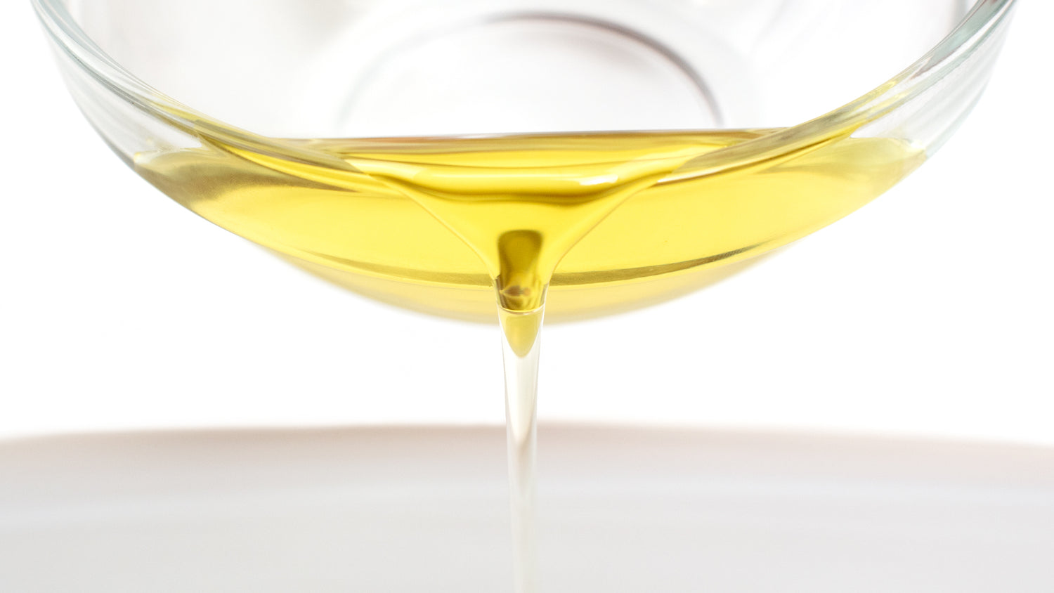 avocado oil in a small glass being poured in front of the camera