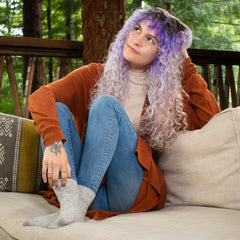 Wavy haired girl lounging on couch with head propped on arm.